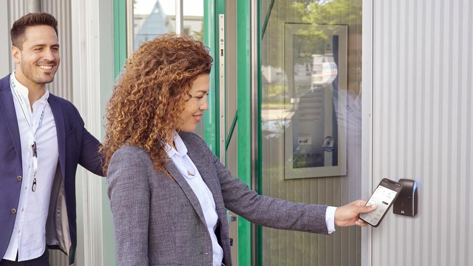 Un téléphone portable est présenté devant un lecteur de contrôle d'accès pour ouvrir la porte.